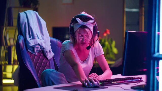 Asleep woman gamer waking up and continuing to play computer video game. Tired teenager sleeping in middle of play. Cybersport at night, addiction to gaming. Late cyber competition. Neon light.