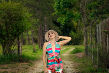 Beautiful and strong woman fighting breast cancer Smiling and happy. In hat on the road and street in the forest. Hairless and bald. live and joy of fighting. Dancing Sexy Dress of flowers in nature.