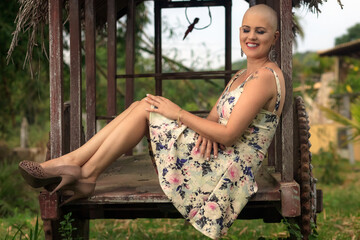 Beautiful and strong mature woman fighting breast cancer disease Smiling and lots of happiness. Hairless and bald. Willingness to live and joy to fight. Sensual dress of flowers in nature in chariot.