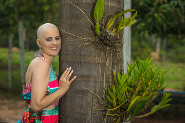Portrait Mature woman, beautiful and strong fight against breast cancer disease Smiling and a lot of happiness. Hairless and bald. Willingness to live and joy to fight. In nature and hugging tree.