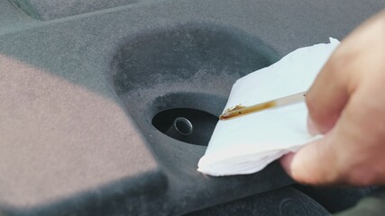 Caucasian Male Checking Engine Oil Level using Metal Dip Stick