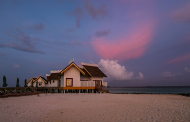 Over water bungalows with steps into amazing green lagoon at sunset time. Crossroads Maldives, july 2021