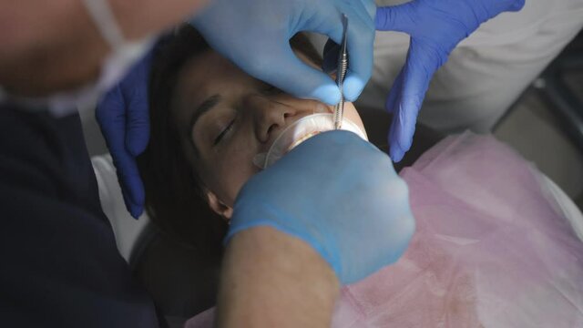 The process of removing a wisdom tooth in a dental clinic. The dentist uses special tools to remove the tooth of a patient sitting in a dental chair.