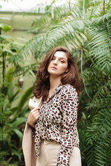 Beautiful pretty girl in a leopard blouse on a background of green jungle