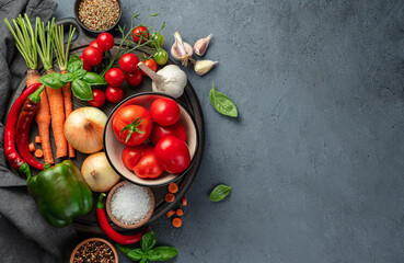 Fresh vegetables, herbs and spices on a cutting board on a dark background. A set of ingredients for making sauce, salad. The concept of cooking recipes.
