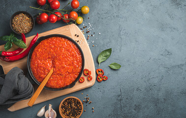 Tomato marinara sauce in a frying pan on a gray-blue background. Italian cuisine. Top view, copy space