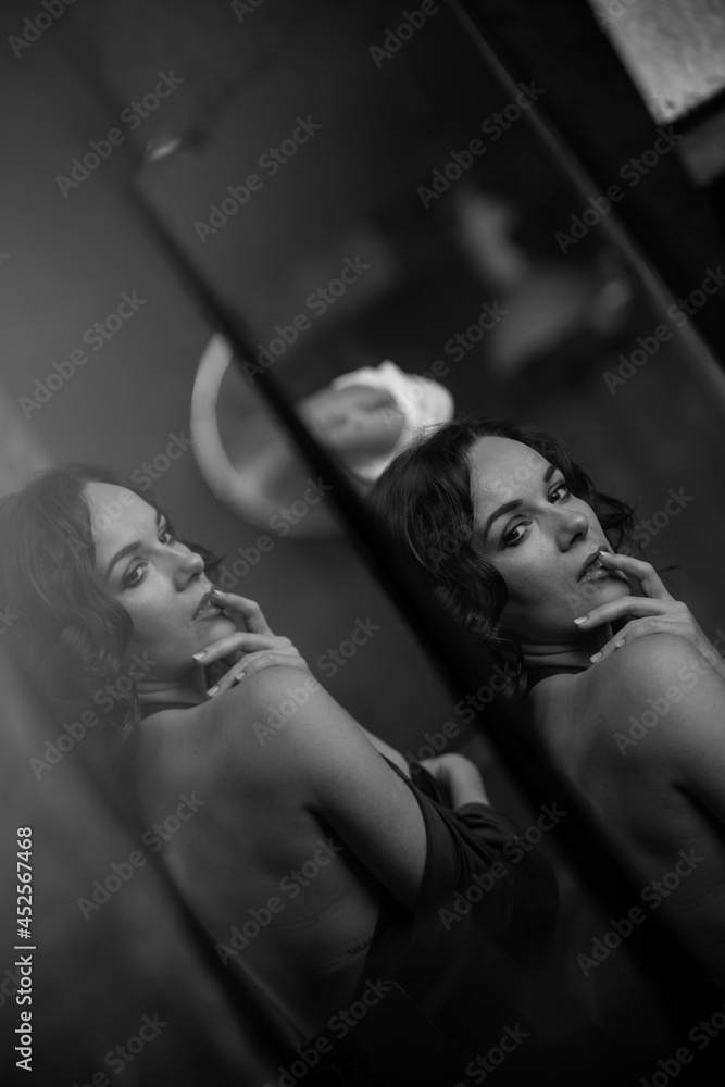 Poster Black and white shot of a sexy Caucasian woman wearing a lingerie top through the mirror