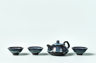 Green tea in a dark turquoise clay teapot and small cups lined on pastel background. Creative minimalist tea ceremony concept. Copy space.