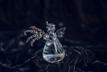 glass vase angel with lavender flowers on black velvet background, glass angel holding a small bouquet of lavender
