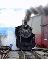 Fototapeta na wymiar View of An Antique Steam Locomotive Warming Up Blowing Steam and Smoke on an Early Spring Morning