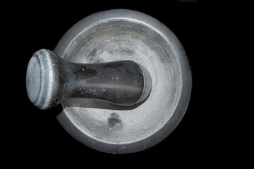 a mortar made of black natural stone lies on a black background. top view. for cooking spices