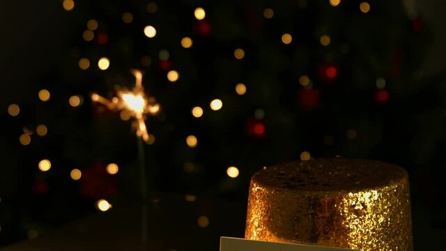 Animation of sparkler and christmas hat and card with copy space over orange spots of light