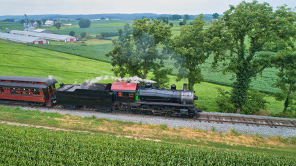 Aerial View of a Steam Locomotive Traveling Across a Fertile Farmland Landscape Blowing Smoke on a Beautiful Summer Day