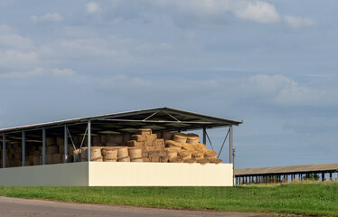 Round bales of straw are stored under a shed. Selective focus.
