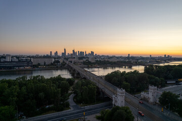 wieżowce w cetrum Warszawy, rzeka Wisła, most Poniatowskiego o zachodzie słońca z lotu ptaka, dron