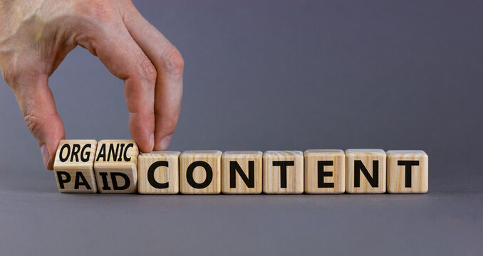Paid or organic content symbol. Businessman turns wooden cubes, changes words 'paid content' to 'organic content'. Beautiful grey background, copy space. Business, paid or organic content concept.