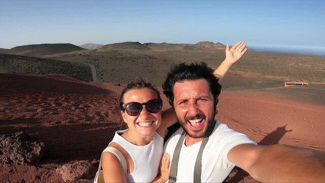 tourist is standing on the Lanzarote valley with red mountains in the national park Timanfaya in Lanzarote, Canary islands and taking selfie photo