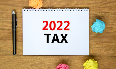 2022 tax new year symbol. White note with words 2022 tax on beautiful wooden table, colored paper, black metallic pen. Business and 2022 tax new year concept.