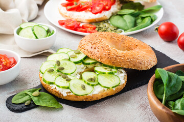 Delicious bagel stuffed with feta, cucumber and pumpkin seeds and spinach leaves on a slate board. Light Vitamin Healthy Snack. Close-up