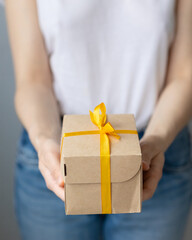 woman holding kraft cardboard boxes with yellow bow or ribbon, food or clothing delivery, modern ways to buy food with delivery, online store with home delivery, women's hands holding boxes of food or