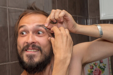 Obraz premium A bearded man cuts his eyebrows