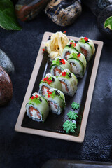 Rolls with salmon and butter cream. Dark background. Vertical photo. A traditional Japanese dish.