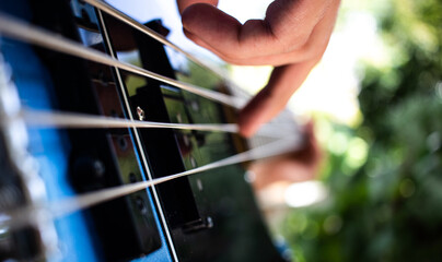 Hands playing bass guitar on open air, playing in a band concept, learning a new instrument concept