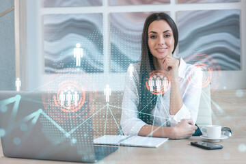 Attractive businesswoman in white shirt at workplace working with laptop to hire new employees for international business consulting. HR, social media hologram icons over office background