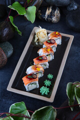 Two types of traditional Japanese rolls. Rolls with smoked salmon and rolls with smoked eel.Creamy cream and cucumber inside the rolls. Dark background.Top view.