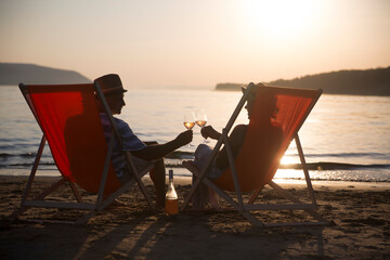 senior couple drink wine and spending time at the beach.