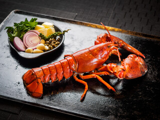 Hot and freshly broilled or baked whole Maine Lobster with vegetable side dish on serving cast iron...
