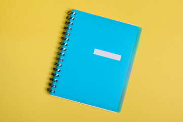 Close-up of a blue colorful organizer, notepad with empty blank sheet for text, isolated on yellow background with copy space. Flat lay