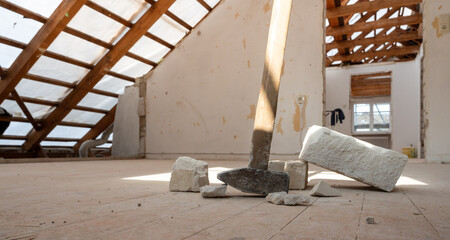 Renovating the attic of a private house. A sledge hammer and some bricks lie on the floor.