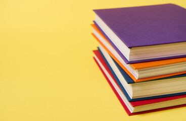 Stack of multicolored books on yellow surface background with copy space for text. Teacher's Day concept, Knowledge, literature ,reading, erudition