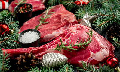 Variety of Christmas Raw Beef Steaks. Ribeye steak, tomahawk, T-bone, with tree and Christmas toys...