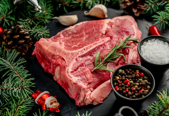 Christmas raw T-bone steak with Christmas tree decorations on stone background