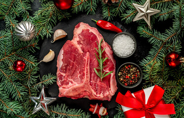 Christmas raw T-bone steak with Christmas tree decorations on stone background