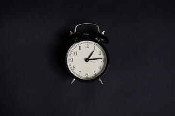 Monochrome composition with a vintage alarm clock on black background with copy space to add text. Back to School and Teachers Day Concepts, Business, Organization, Time Management. Flat lay. Top view