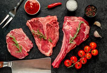 A variety of raw steaks. Ribeye steak, tomahawk, T-bone, on a stone background