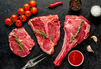 A variety of raw steaks. Ribeye steak, tomahawk, T-bone, on a stone background