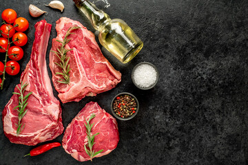 A variety of raw steaks. Ribeye steak, tomahawk, T-bone, on a stone background with copy space for your text