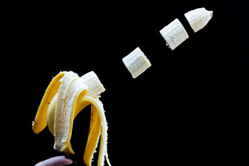 Banana fatiada descascada pela metade e fundo preto. 
