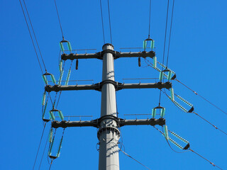 Fragment of an electric pole with wires on a background of blue sky in sunlight