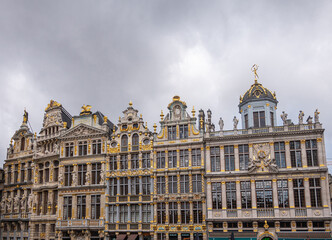Fototapeta na wymiar Brussels, Belgium - July 31, 2021: 6 historic iconic facades of guild houses on NW-side of Grand Place under heavy gray cloudscape. Lots of sculptures and golden ornaments.