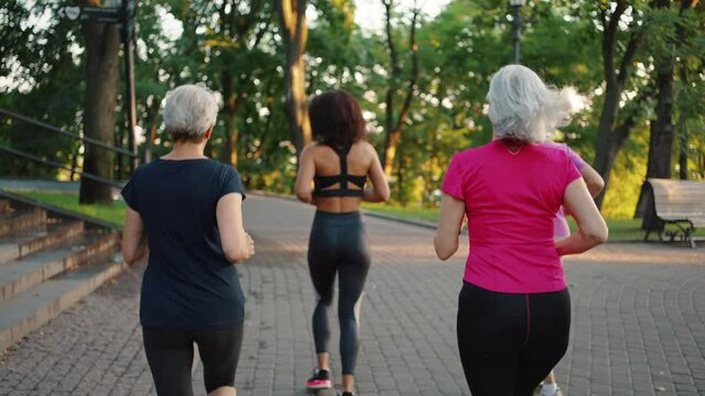 Active and healthy lifestyle. Group of mature women running with trainer in park, practicing sport activities together