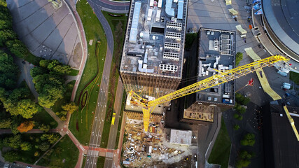 Modern, high-rise glass building under construction, aerial view. Construction of a business skyscraper in European city.  Beautiful skyline view. High Tower Crane attached to building.  © SARATSTOCK