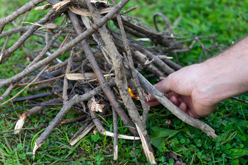 Making a fire with matches. A man's hand sets fire to dry branches with matches