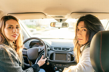 Fototapeta na wymiar Two Latina women friends in a car seen from the back seat.