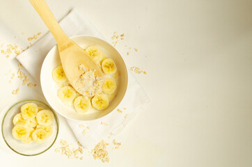  Oatmeal porridge with banana slices on white background.