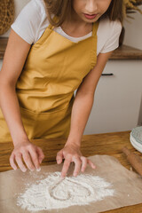 A woman baker or pastry chef draws a heart from flour on the table. Bakery and pastry shop